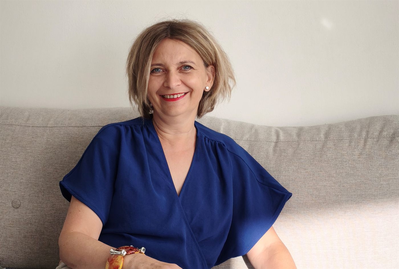 Ráb Orsolya mosolyogva a kanapén